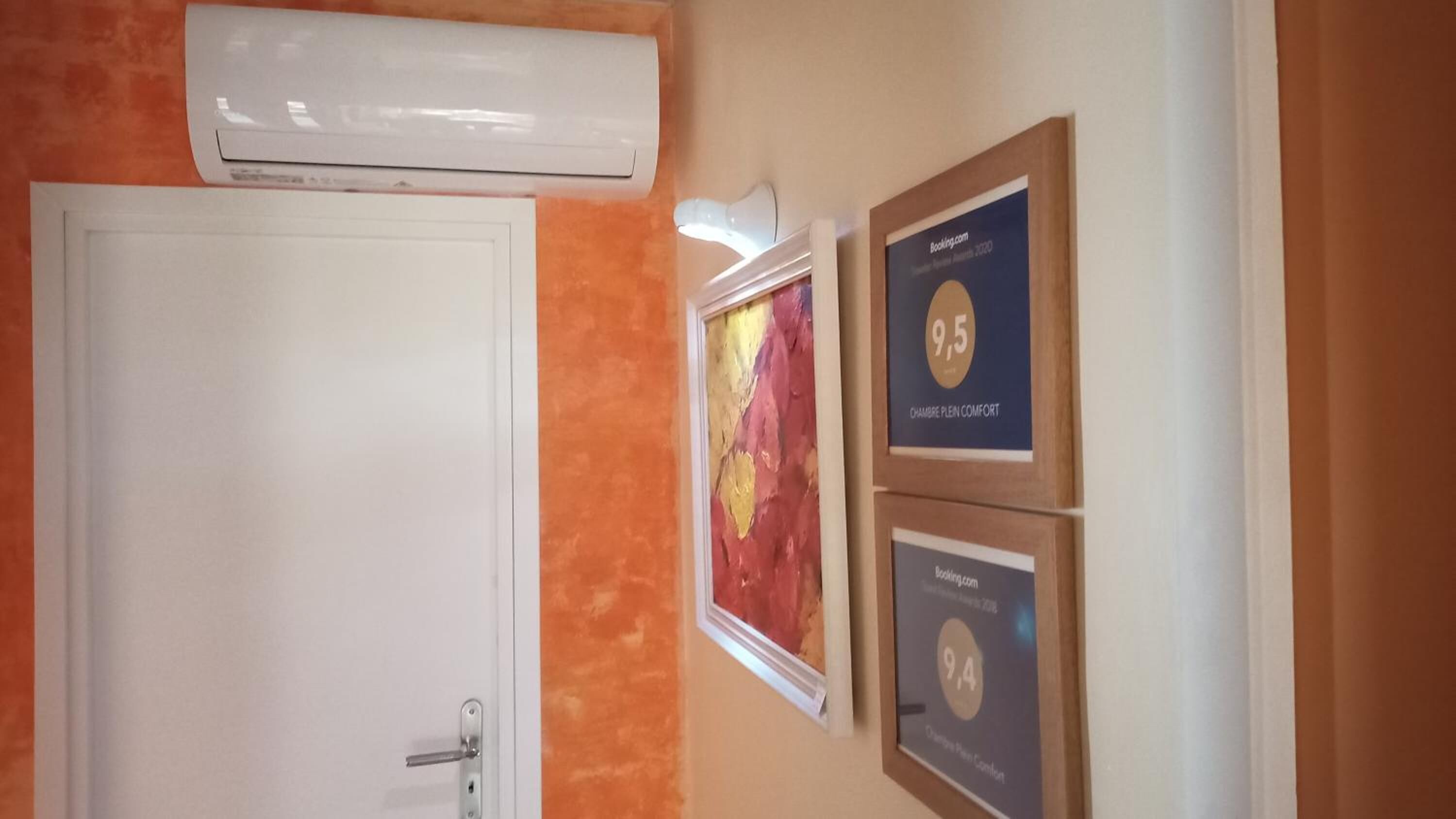 A hallway with an air conditioning unit above a white door, and two framed awards on the wall.