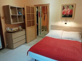 Un dormitorio con cama, armario, espejo y un cuadro en la pared.