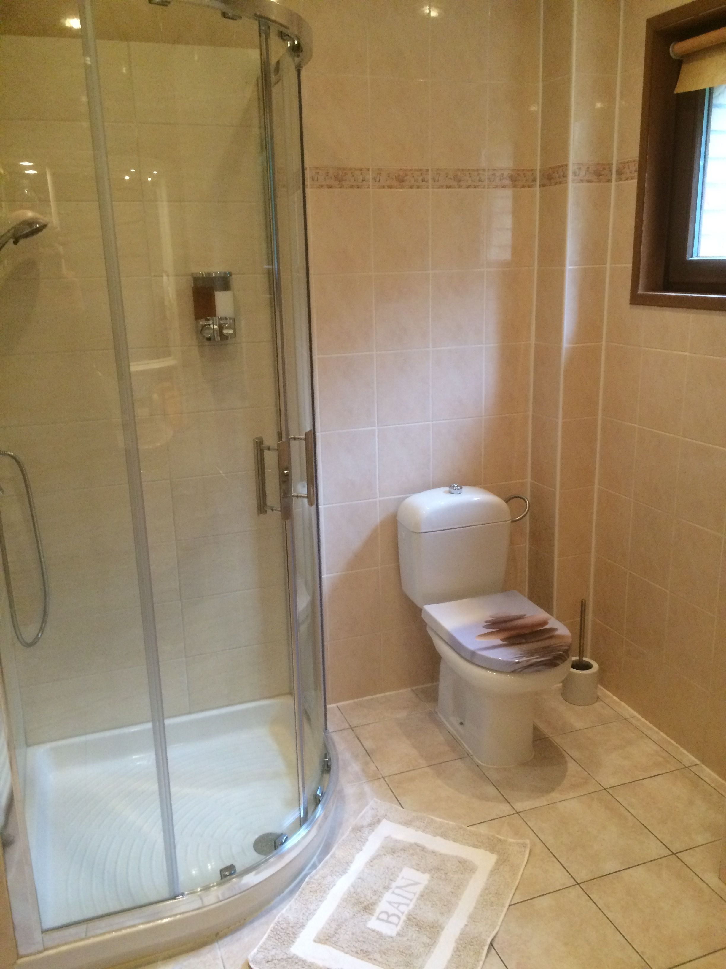 A bathroom with a glass-enclosed shower, a toilet, and a bidet.
