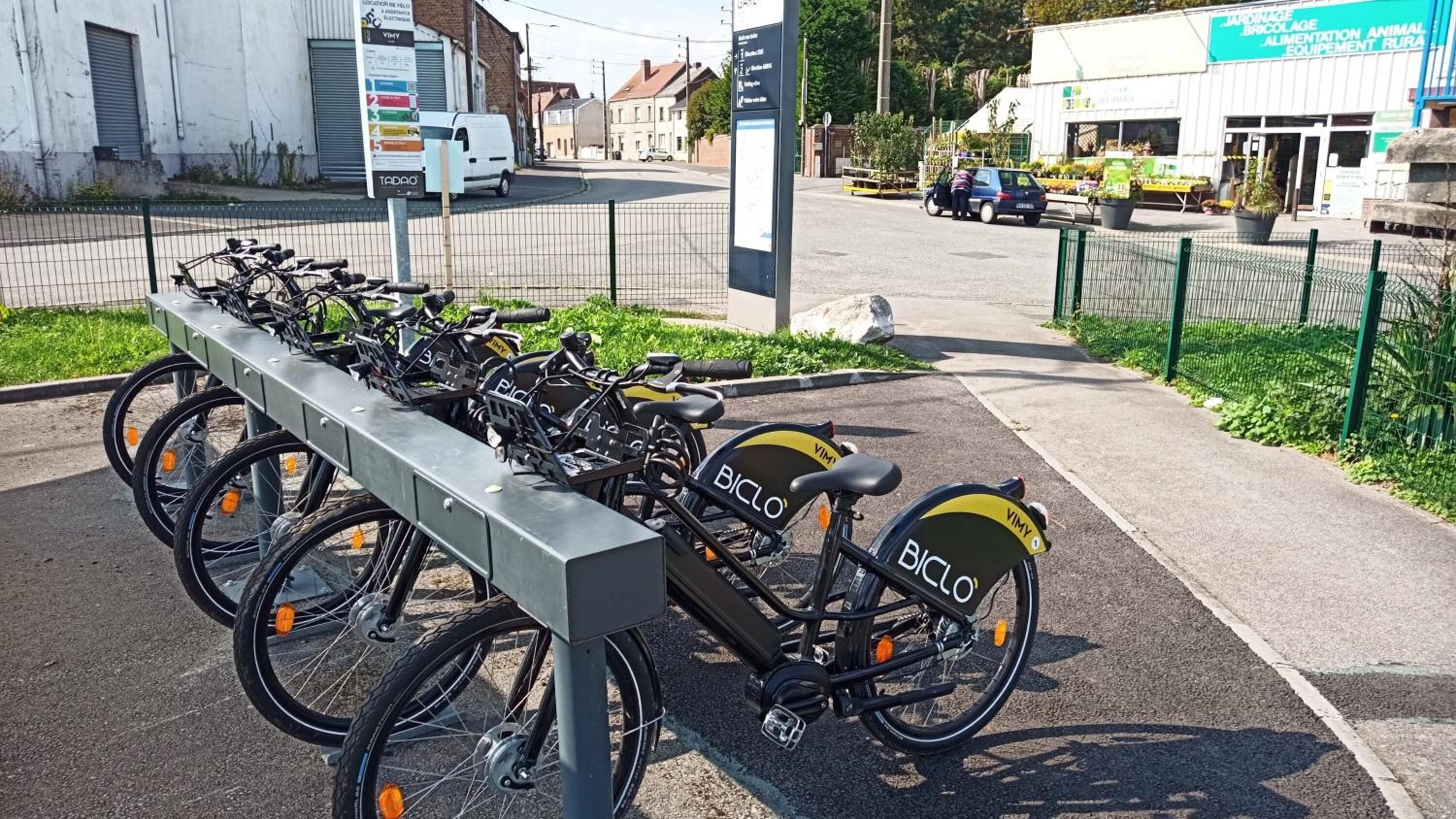 A bicycle parking area with multiple bikes and a signboard.