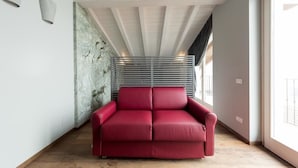 Un sofá rojo en una habitación moderna con una pared de listones y un techo de madera.