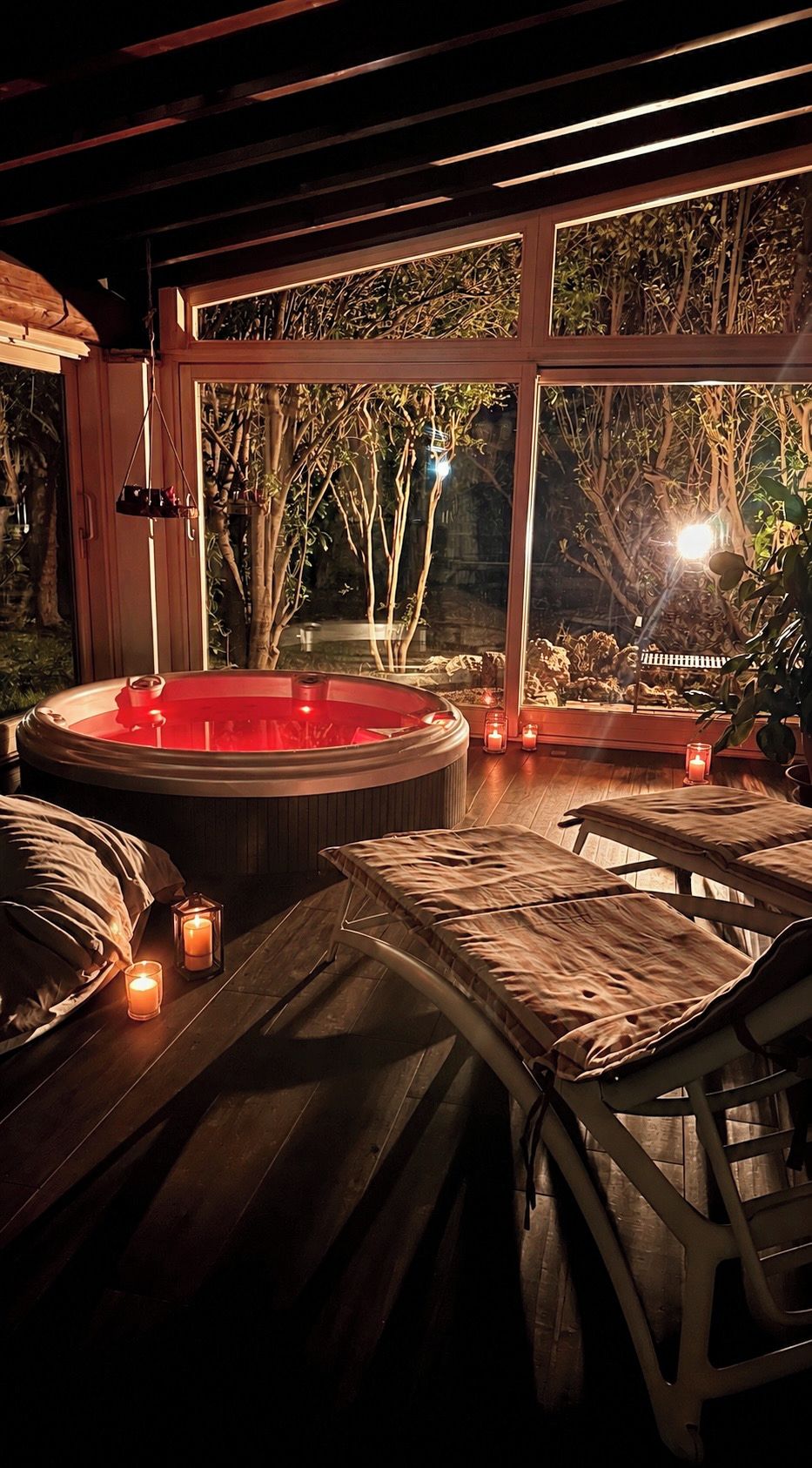 Una habitación acogedora con hidromasaje, muebles de madera y vistas a árboles a través de amplias ventanas.