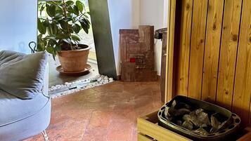 A room with a wooden bench, a potted plant, a metal sculpture, and a fireplace.