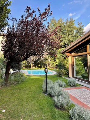Un jardin avec une piscine, un lampadaire et un bâtiment doté de grandes fenêtres.