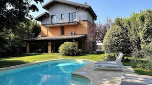 Ein zweistöckiges Haus mit Schwimmbad und Sitzgelegenheit im Freien.