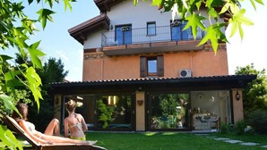 Una casa de dos pisos con un balcón, un porche cubierto y un jardín.