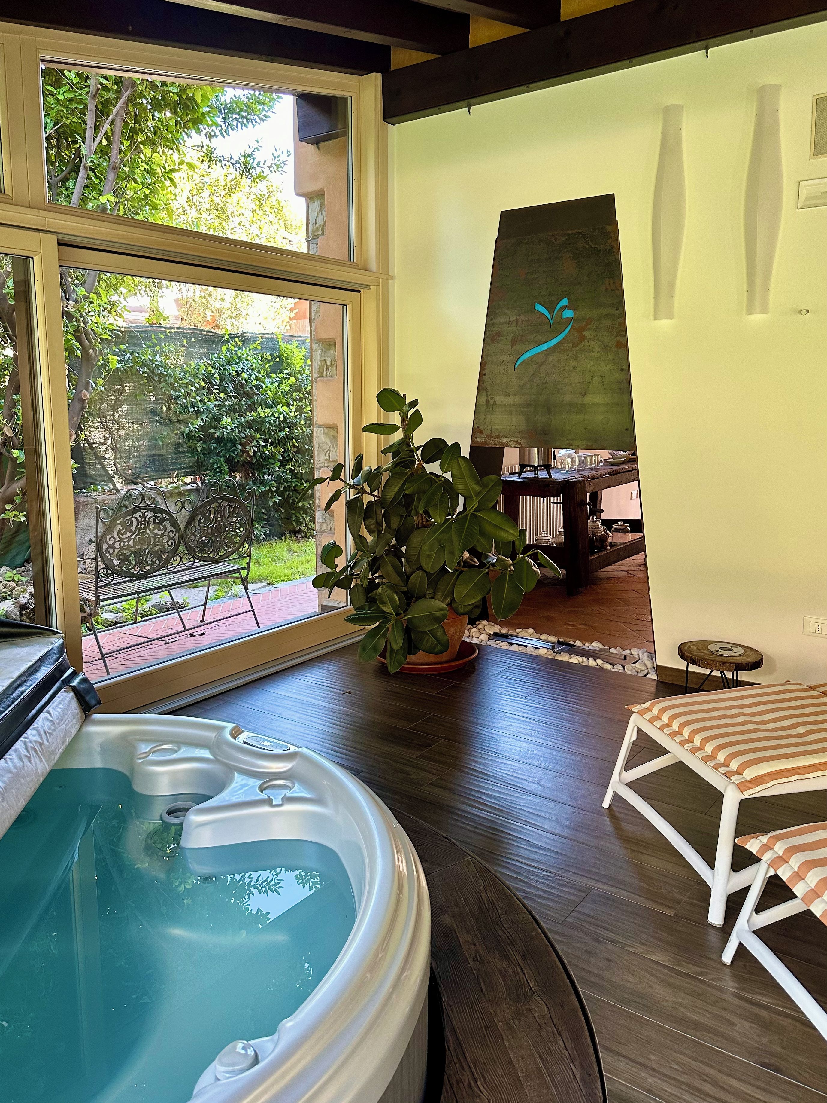A room with a hot tub, a potted plant, a striped chair, and a painting on the wall.