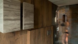 Un baño moderno con paneles de madera y una cabina de ducha de vidrio.