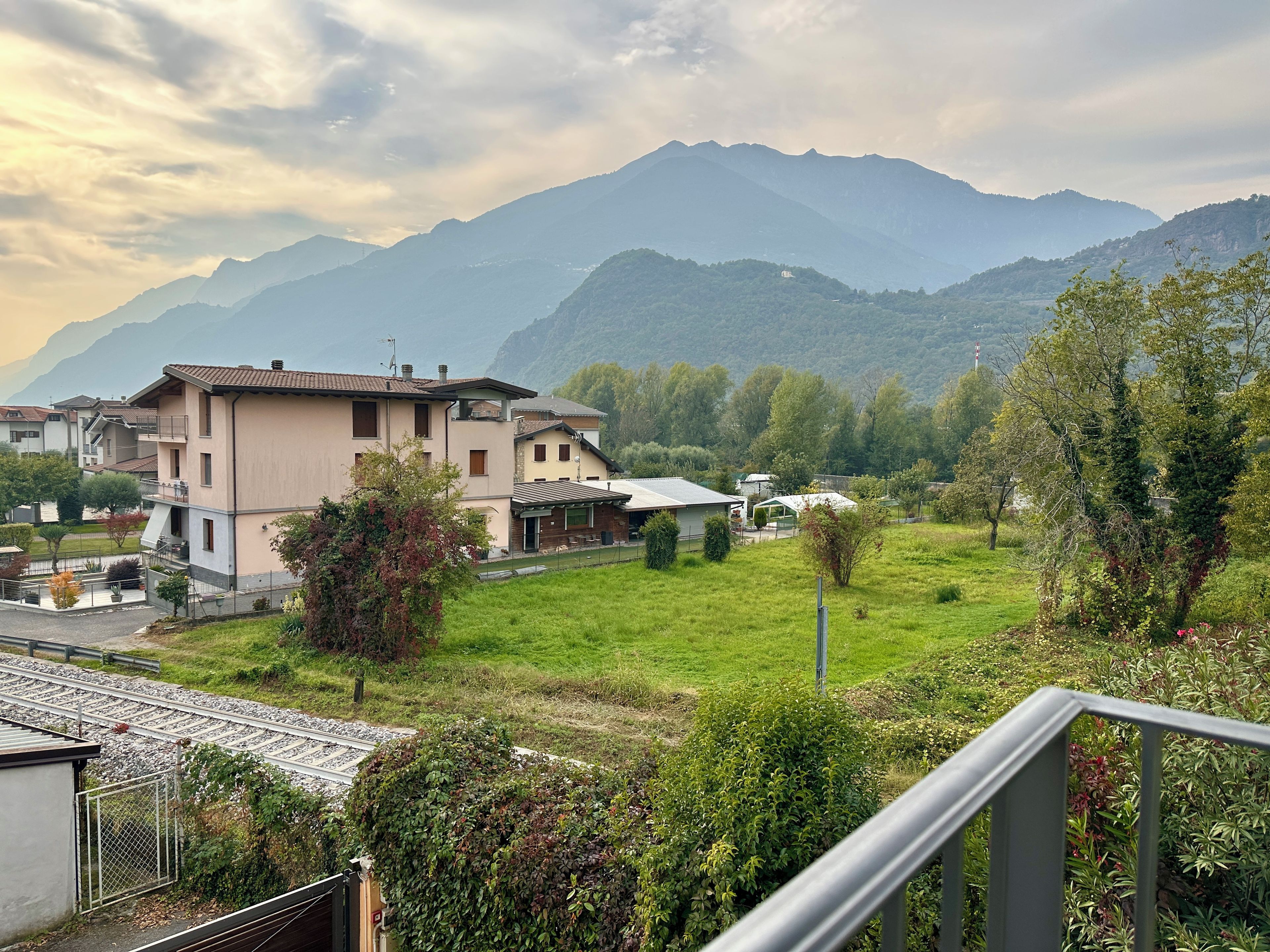 A residential area with houses, a grassy field, and mountains in the background.
