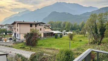 A residential area with houses, a grassy field, and mountains in the background.