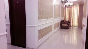 A hallway with a dark door, patterned wallpaper, and a row of armchairs. - Georgian Palace (Kutaisi)