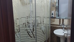 A bathroom with a glass-enclosed shower, a toilet, and a sink. - Georgian Palace (Kutaisi)