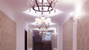 A hallway with a chandelier, a radiator, and a staircase. - Georgian Palace (Kutaisi)