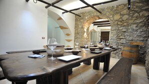A long wooden table with wine glasses and bowls, set in a room with stone walls and a rustic ambiance. - Hotel Gentile (Agerola)