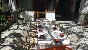 An outdoor dining area with wicker chairs and a long table set for a meal. - Hotel Gentile (Agerola)
