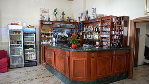 A bar area with a counter, shelves with bottles, and a refrigerator. - Hotel Gentile (Agerola)