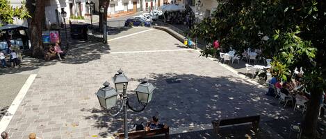 A cobblestone square with benches, a street lamp, and buildings in the background.