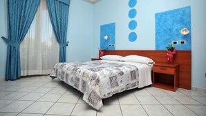 A bedroom with a bed, curtains, a nightstand, wall art, and a wall-mounted light fixture. - Hotel Gentile (Agerola)