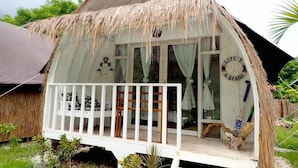 A thatched-roof bungalow with a white porch and a sign reading "LIFE'S A BEACH". - Maleo Moyo Seaside Resort (Moyo)