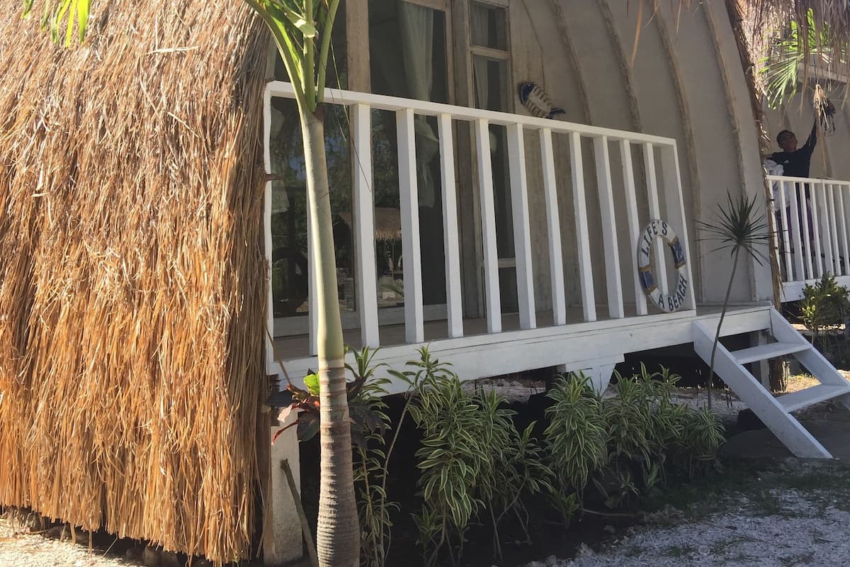 Una estructura de techo de paja con un balcón blanco y un letrero de boya salvavidas.