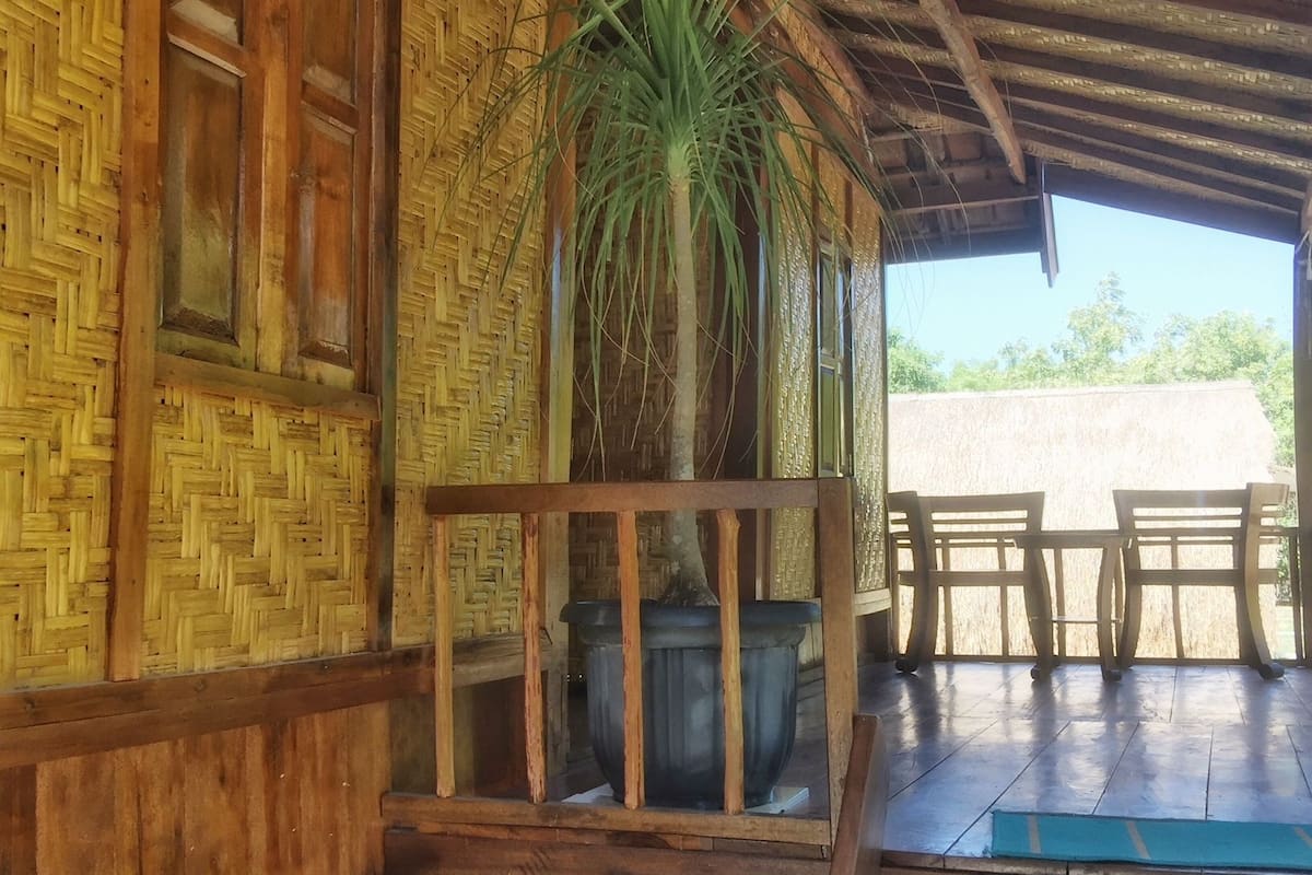 Una estructura de madera con un muro tejido y techo de paja.