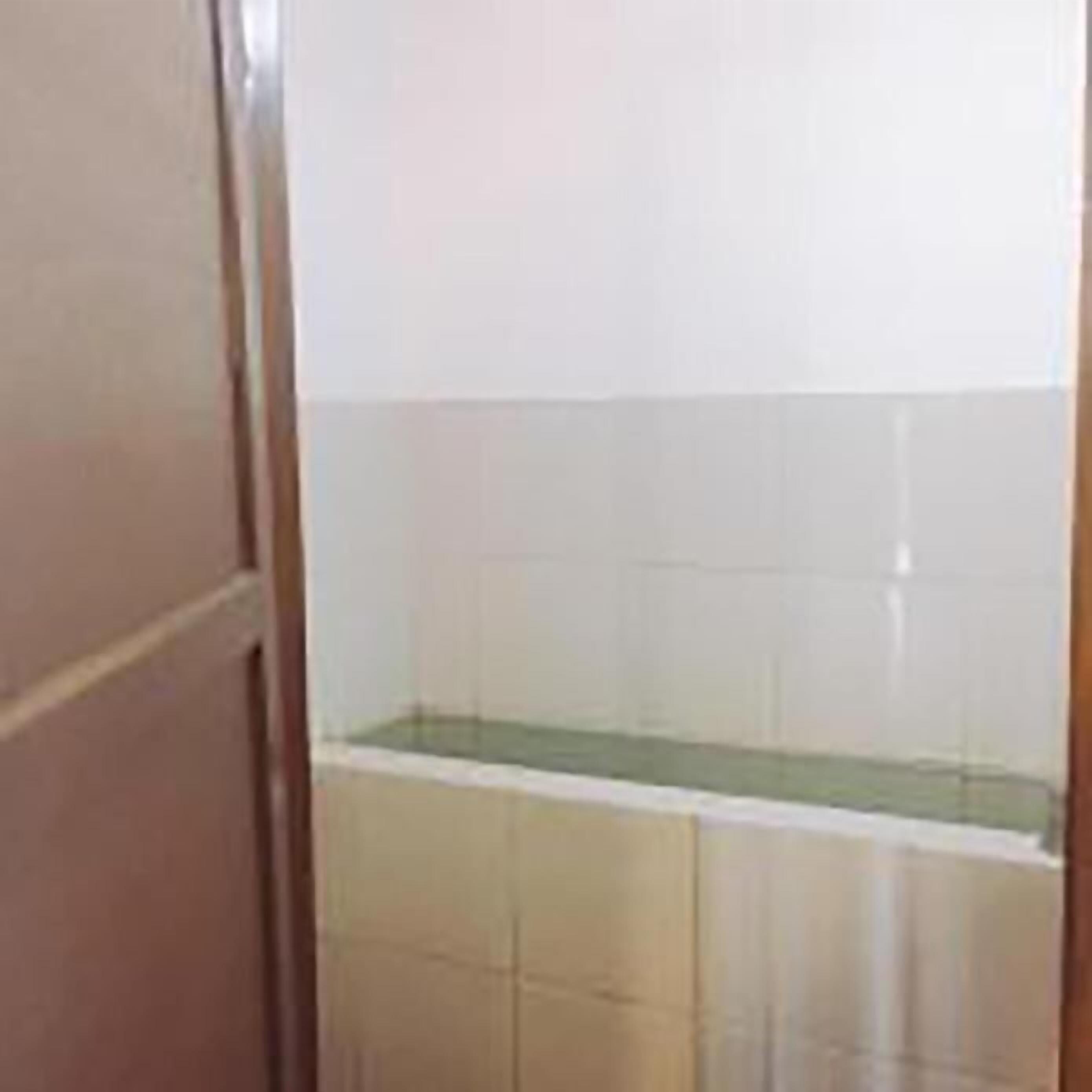 A bathroom with white tiles, a green sink, and a wooden door.