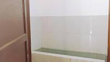 A bathroom with white tiles, a green sink, and a wooden door.