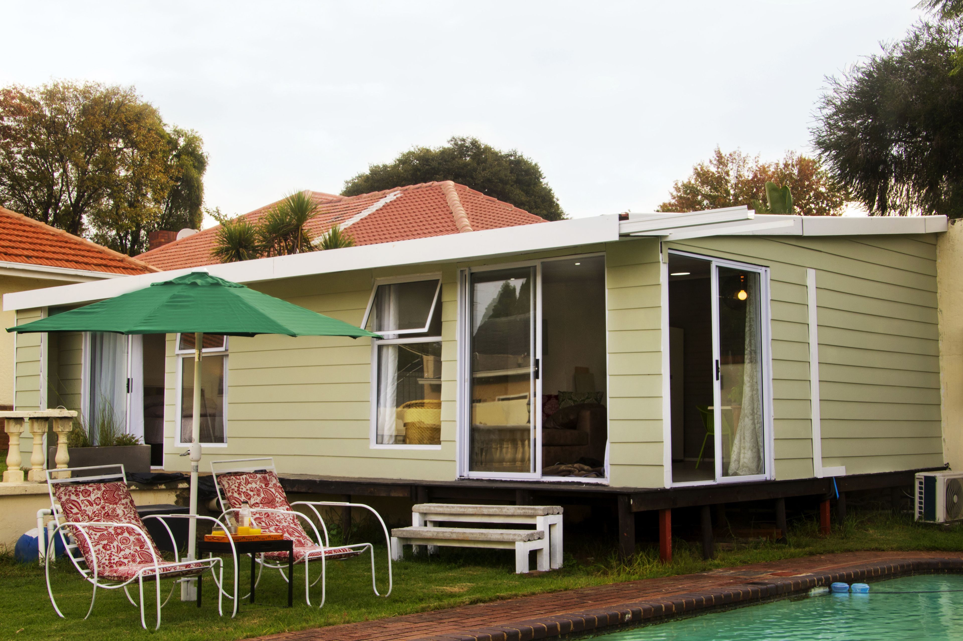 Een gelijkvloers huis met een zwembad, terras en overdekte patio.