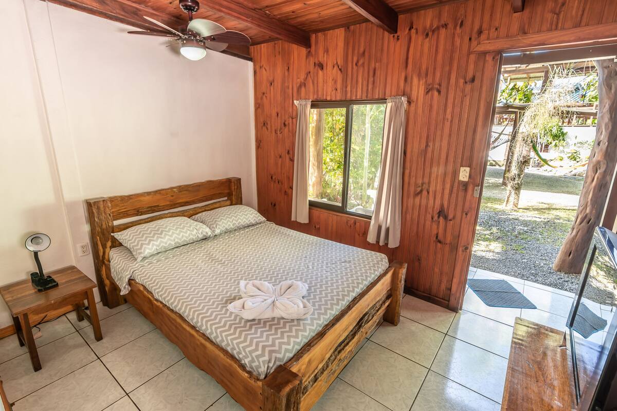 A wooden-framed bed with a chevron-patterned bedspread and a towel on the bed.