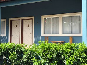 Un edificio con dos puertas, una ventana y una siega en primer plano.