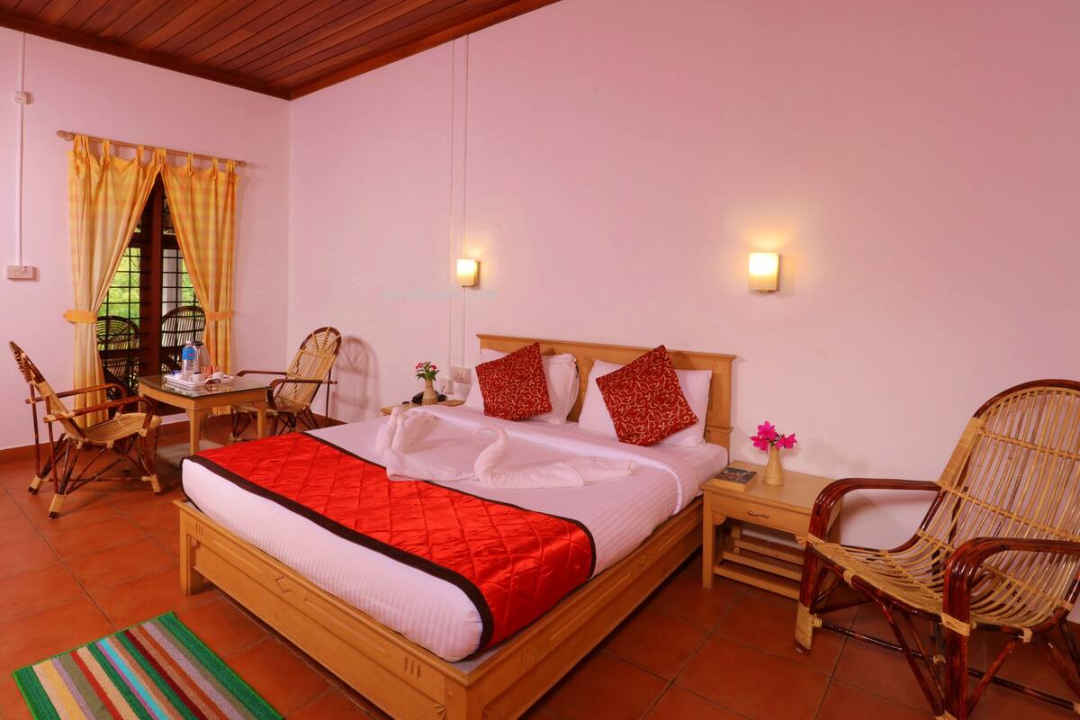 Una habitación de hotel con una cama, dos sillas, una mesa y una ventana con cortinas.