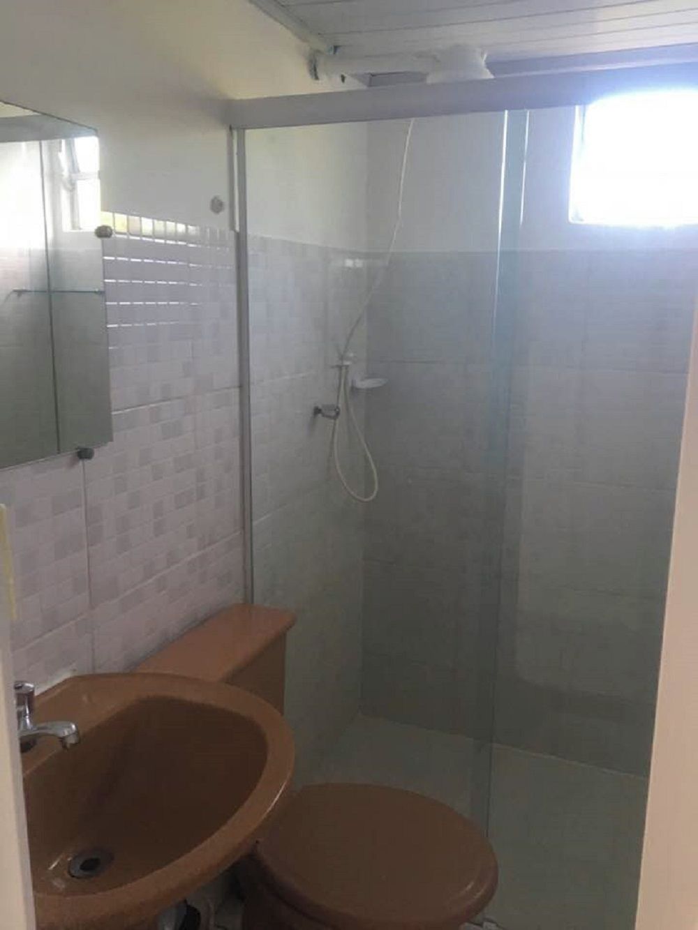 A bathroom with a glass-enclosed shower, a sink, and a toilet.