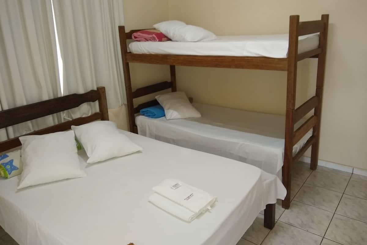 A room with two bunk beds and a single bed, each with white bedding.