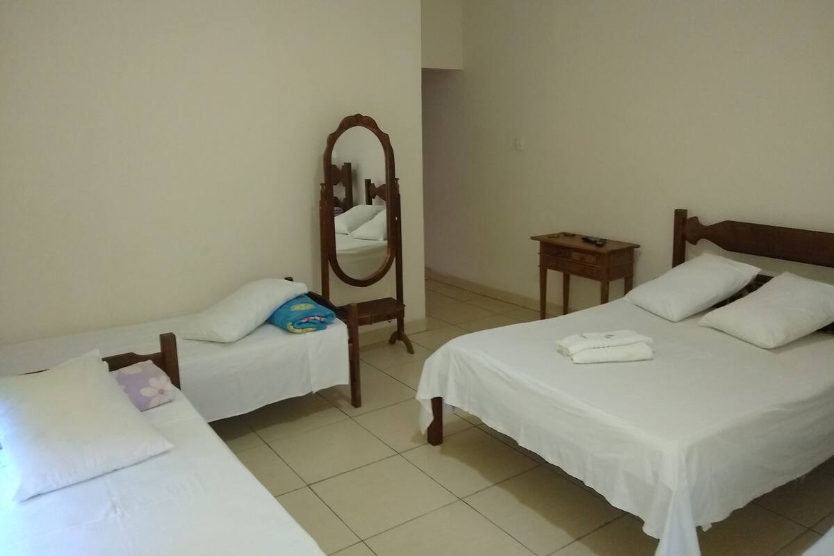 A hotel room with two single beds, a wooden nightstand, a mirror, and a small table.