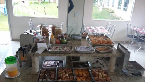 A buffet setup with various food items and condiments. - Pousada Clube Santa Cruz (Santa Cruz de Minas)