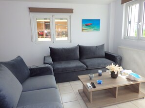 A modern living room with a grey sofa, a wooden coffee table, and a painting of a beach scene.