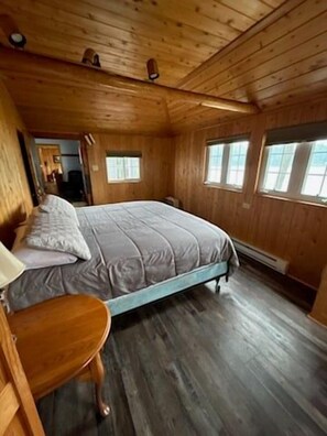 A wooden cabin bedroom with a bed, a nightstand, and a window.