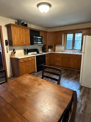 A kitchen with wooden cabinets, a microwave, a sink, and a dining table.