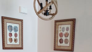 A round dining table with a metal bowl centerpiece, surrounded by four stools with black metal legs. Two framed botanical prints are hung on the wall above the table. - Modern Beach Property recently updated (Surfside Beach)