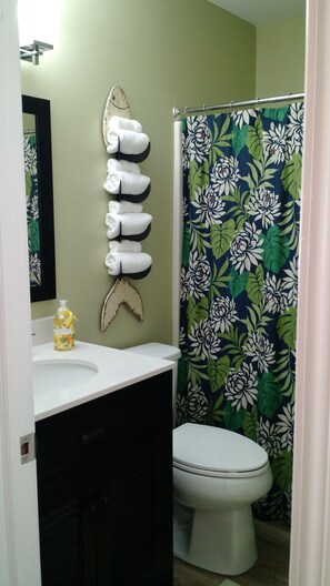Une salle de bain équipée de toilettes, d’un lavabo et d’un rideau de douche à motifs floraux.