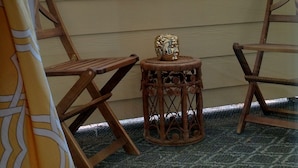 A view through a window of a room with a small table and two chairs, a patterned curtain, and a blue house in the background. - Modern Beach Property recently updated (Surfside Beach)