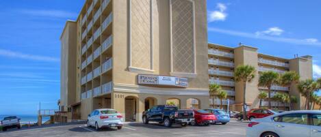 A hotel with multiple floors, a sign reading "Pirates Cove," and a parking lot with several cars.