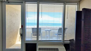 Ein Zimmer mit großem Fenster, einer Tür und einem Lüftungsgitter.