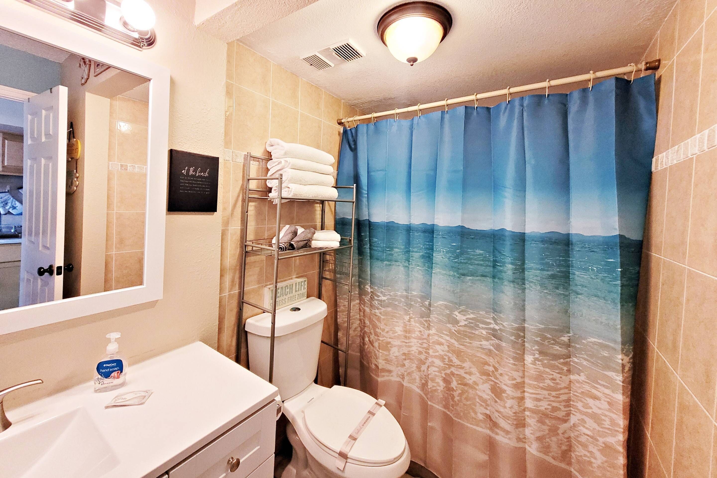 A bathroom with a sea-themed shower curtain, a white sink, and a towel rack.