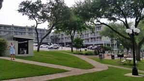 A residential area with a multi-story building, a small kiosk, and a paved pathway.