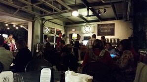 A restaurant interior with tables, chairs, and a bar area. There is an exit sign and a sign for a wine bar.