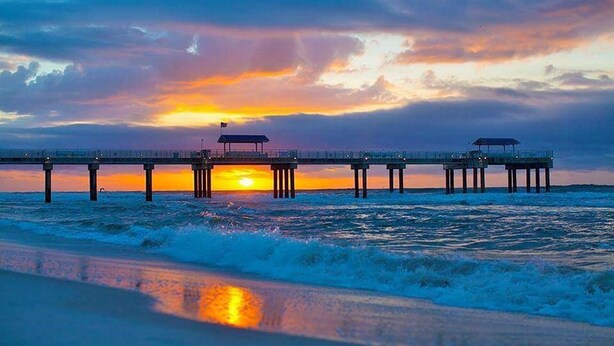 A pier extending into the ocean with a sunset in the background. - 🔥 Beautifully Remodeled Grand Beach LOWEST Rates 🦀 Pool & Heated HotTub👙 (Gulf Shores)