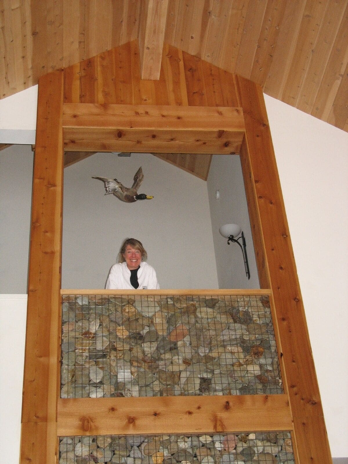 Ein Zimmer mit Holzboden, einer Steinwand und einer Person im unteren Bereich.