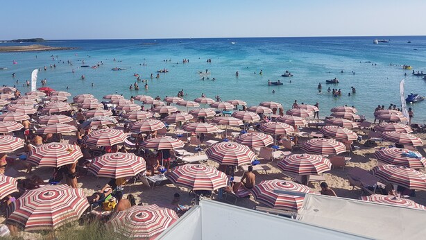 A crowded beach with numerous striped umbrellas and people in the water. -  Full comfort cottage a few steps from the sea and from the center (porto cesareo)