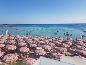 A crowded beach with numerous striped umbrellas and people in the water. -  Full comfort cottage a few steps from the sea and from the center (porto cesareo)